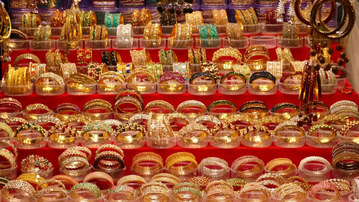 Rows of gold-toned and glass bangles stacked in clear boxes on a red-draped stall near Charminar, Hyderabad